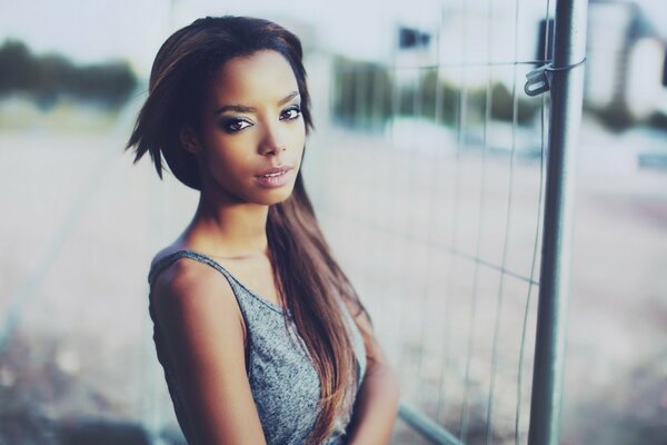 Dark-haired girl on the background of a metal gate