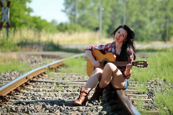 Jolie fille avec une guitare sur les rails