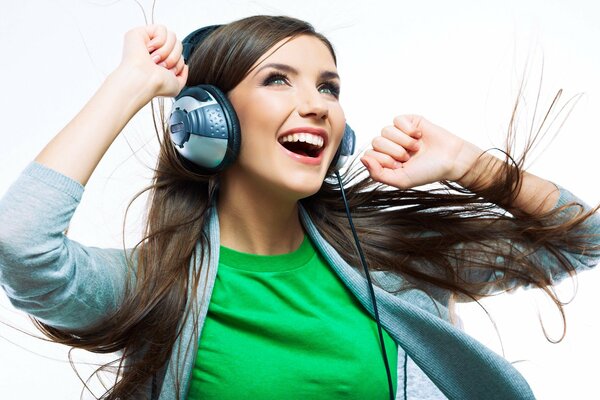 A girl with headphones listens to music and rejoices