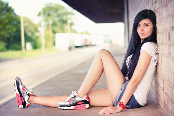 Fille en baskets assis mur