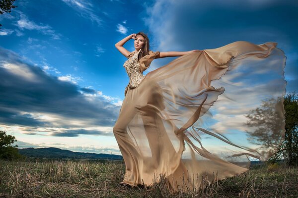 Ragazza in bel vestito in posa contro il cielo