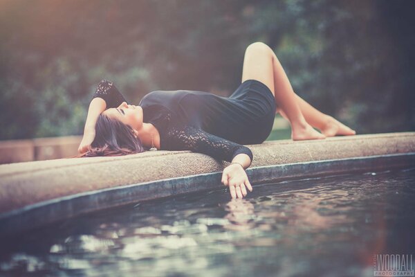 La jeune fille se trouve magnifiquement à la fontaine