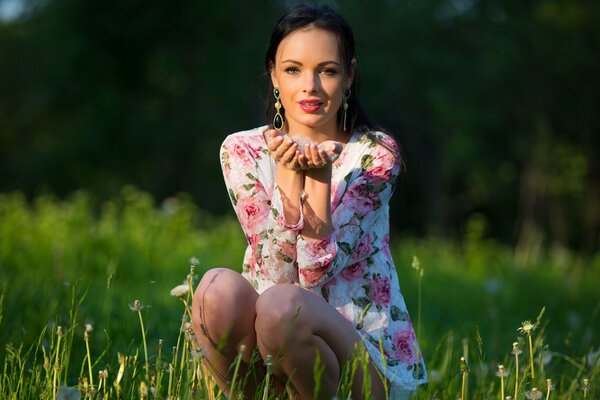 Cute brunette in a dress with flowers in the field