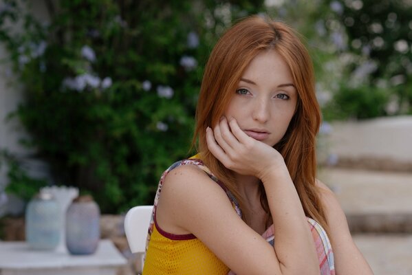 Red-haired beauty Natalie on the background of a flowering shrub