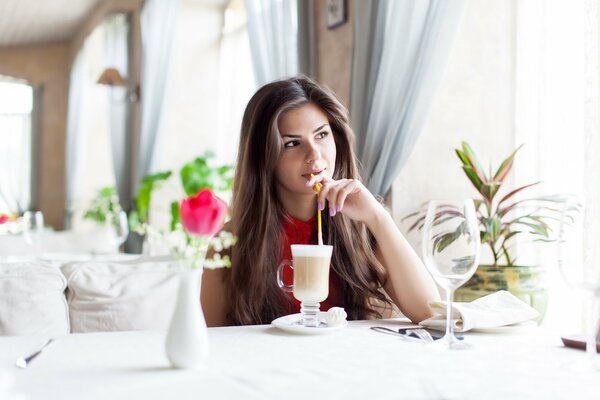 A girl in a restaurant, drinking a cocktail