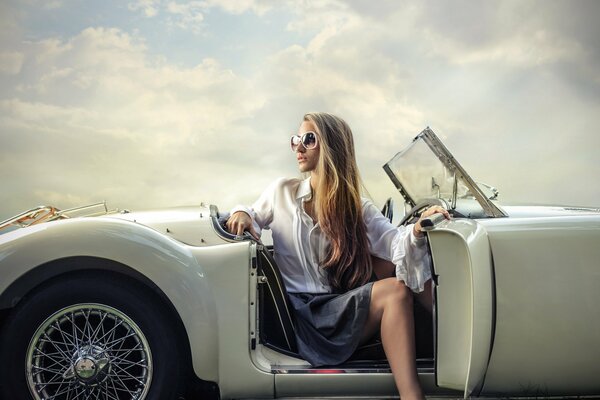 Mädchen mit Brille posiert auf dem Hintergrund eines weißen Autos