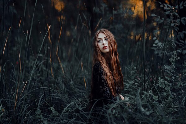 Red-haired girl on the background of darkened nature