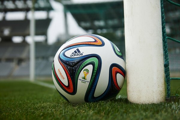 The soccer ball is lying near the goal post