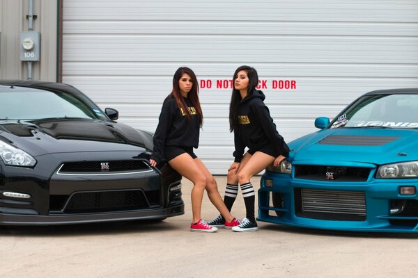 Dos chicas posando en los coches frescos