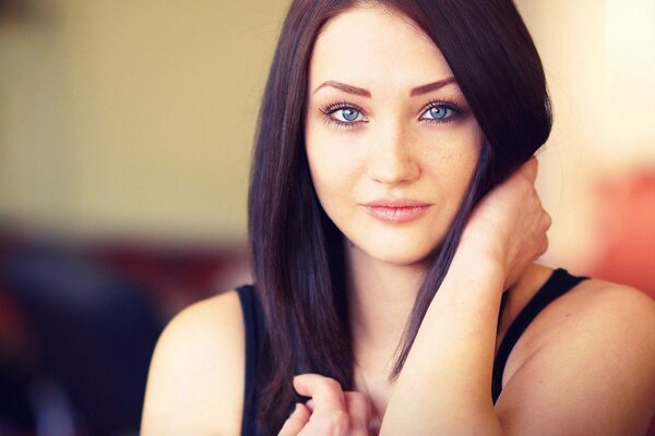 Chica de ojos azules sostiene su cabello con la mano