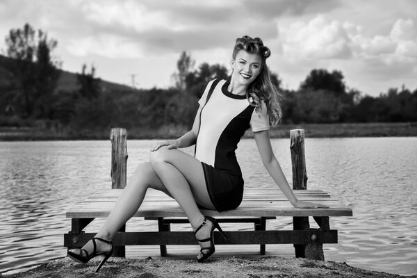 The girl is sitting on a bench on the river bank