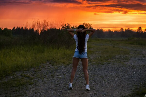 Una hermosa chica deportiva, en el contexto de un hermoso paisaje: la puesta de sol eterna y bytt pueden acercarse a las nubes y la lluvia de verano