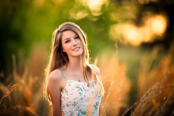 A girl in a dress poses in a field