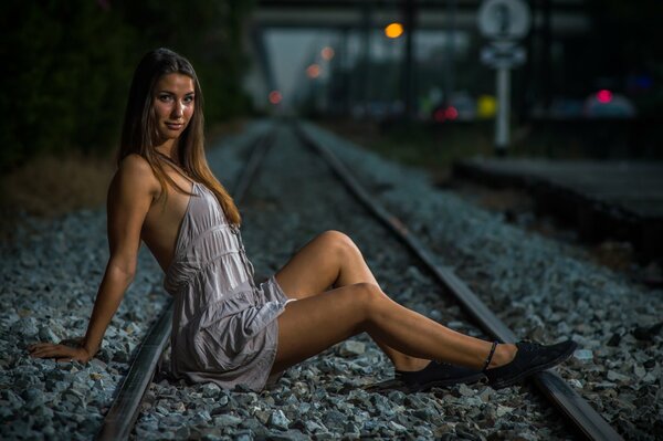 Fille aux cheveux longs assis sur les rails