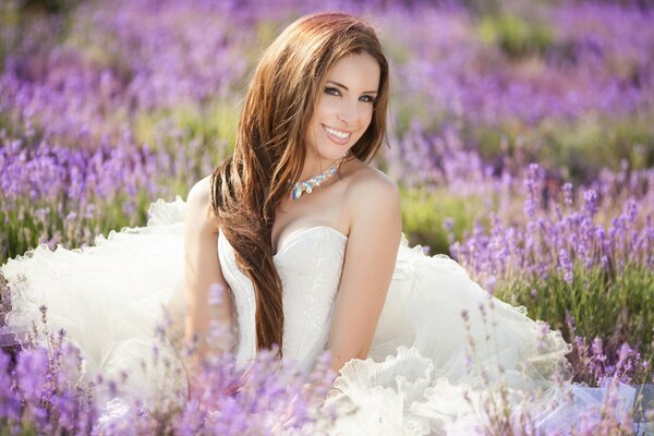 Ragazza in abito bianco si siede in un campo di lavanda