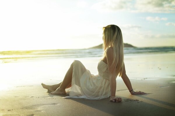 Ragazza in sundress si siede sulla sabbia