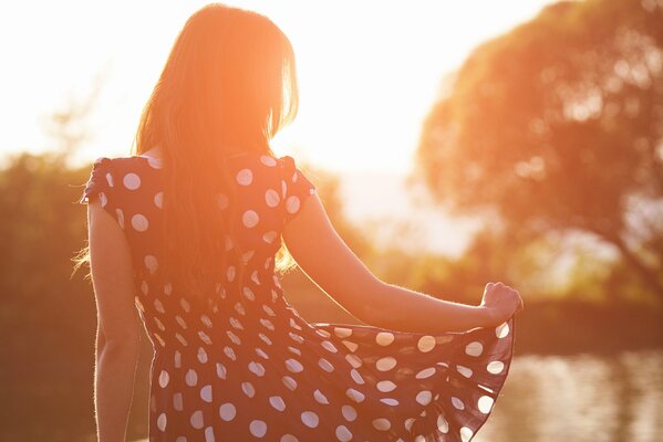 Brown-haired woman in a dress on the river in the morning