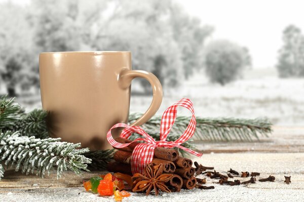 Palitos de canela junto a una taza y una rama de abeto