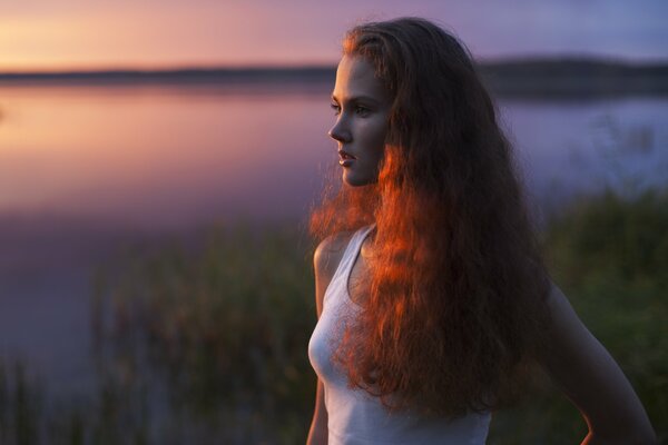 Red-haired girl at the evening lake