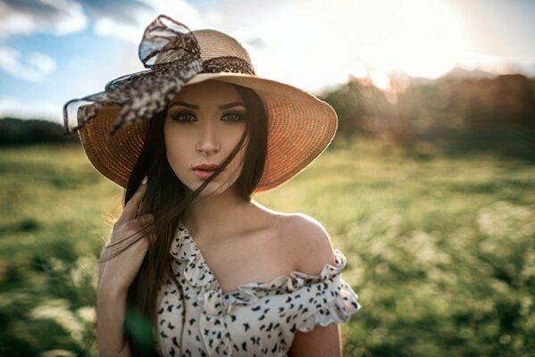 Ragazza con i capelli lunghi e in un cappello in un prato