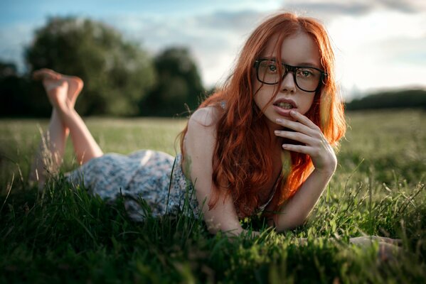 Rousse fille à lunettes se trouve sur l herbe