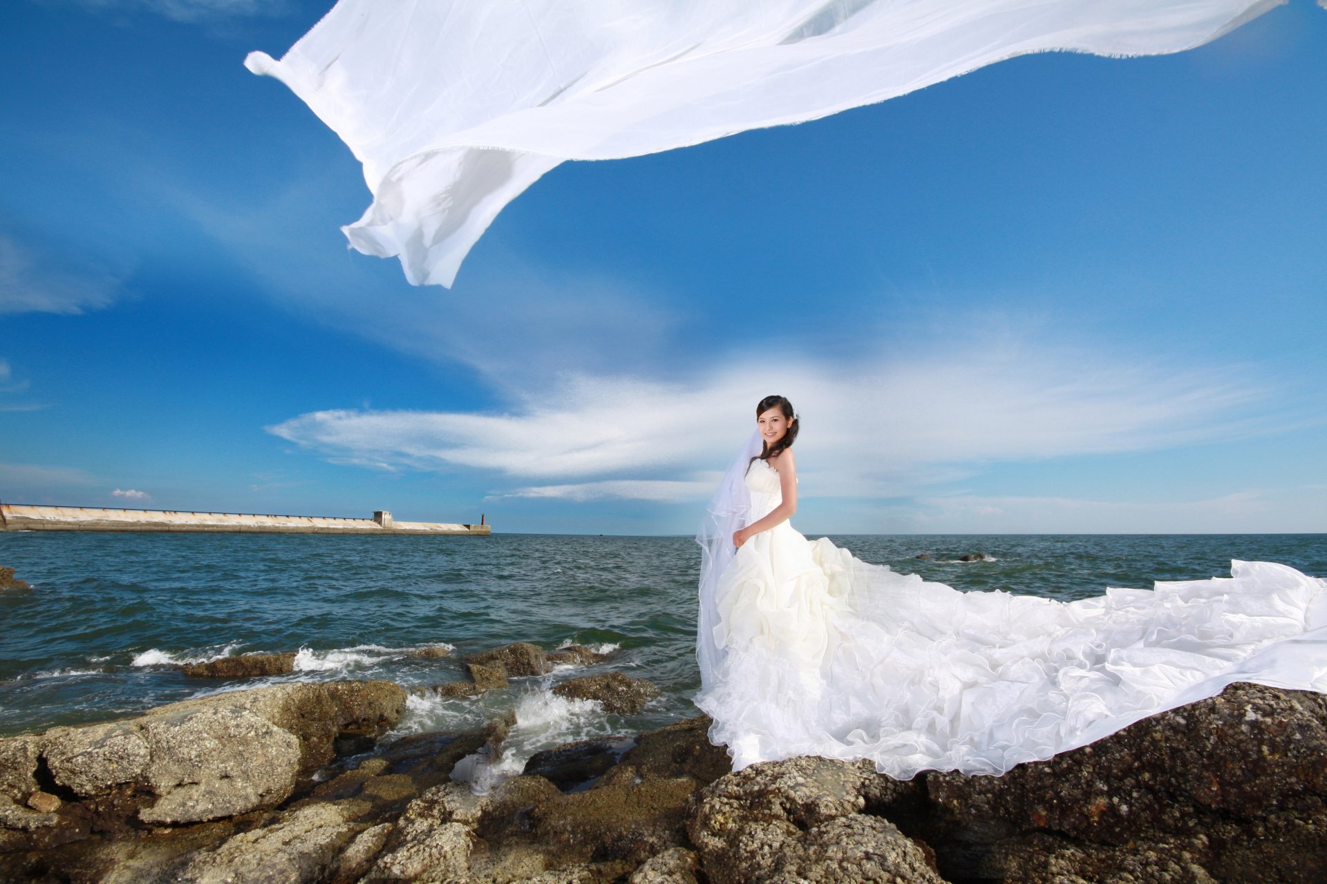 chica asiático vestido de novia blanco piedras mar olas cielo nubes