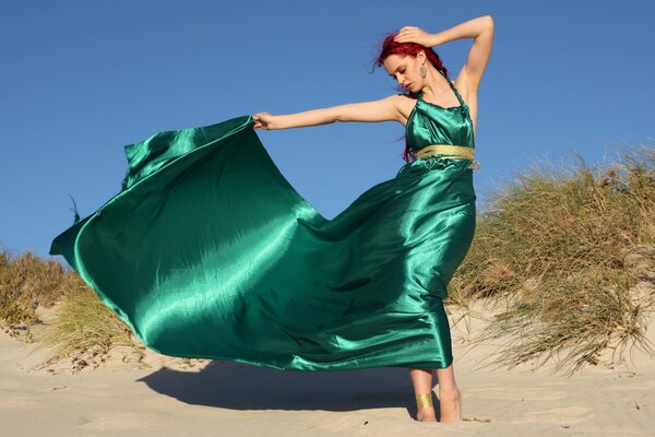 Mädchen posiert im Sand. Grünes Kleid Schleppe