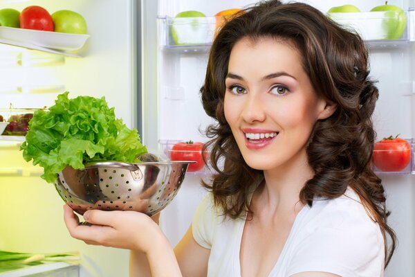 Chica en el refrigerador sostiene un tazón de ensalada