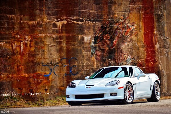 White Chevrolet Corvette C6 on the background of a grunge wall with graffiti