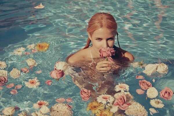 A girl with flowers in her hands in the water