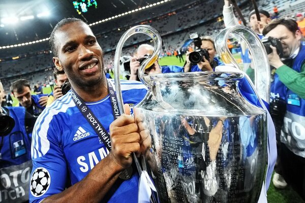 Didier Drogba holds the cup on the pitch