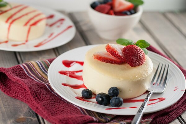 Postre redondo en un plato con fresas y arándanos