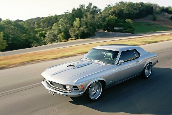 Silberner Mustang Ford 1970, der auf der Autobahn fährt