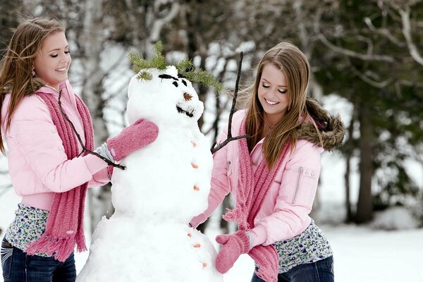 Gemelli in guanti scolpiscono un pupazzo di neve