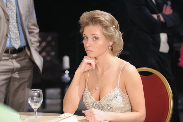 An actress in a restaurant , a glass of white wine