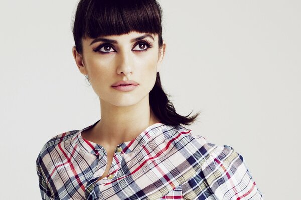 Penélope Cruz en una camisa a cuadros, con el pelo en una cola de caballo