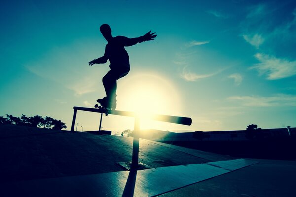 Skateboarder führt Tricks vor dem Hintergrund der Sonne durch