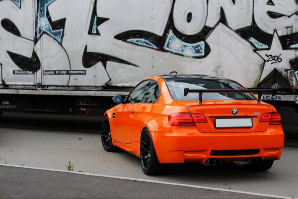 A bright orange car on the background of a graffiti wall