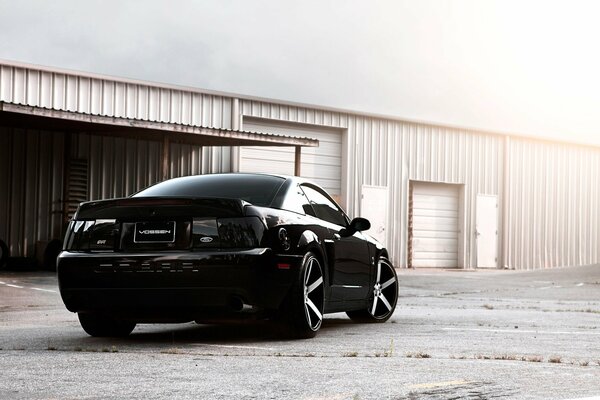 Ford Mustang noir sur fond de hangar