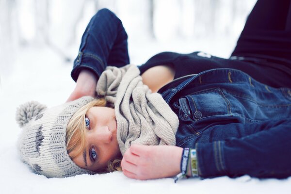 Chica con sombrero yace en la nieve