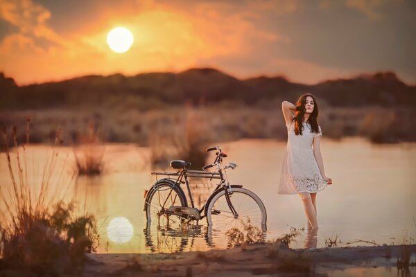 Ragazza con la bicicletta sulla riva dello stagno