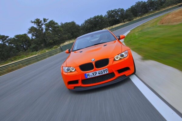 An orange BMW is driving on the road