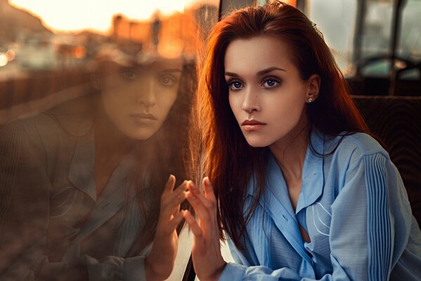 A brunette in a blue shirt looks out the window