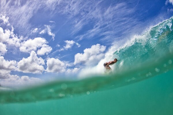 Surfer on the crest of a wave between the sky and the water