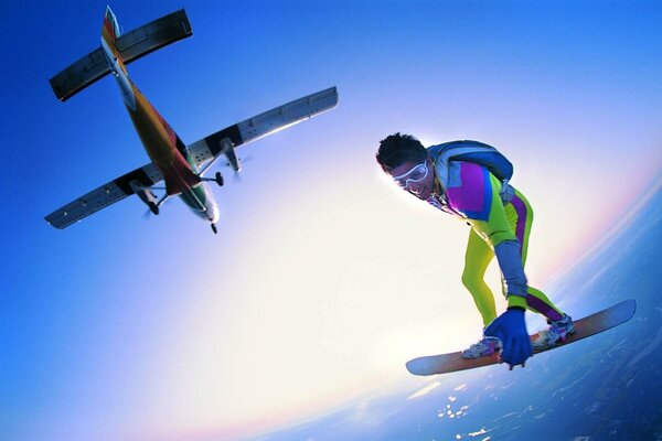 An athlete flying in the sky under an airplane