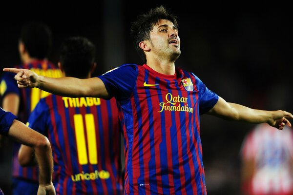 David Villa points his hand at the goal