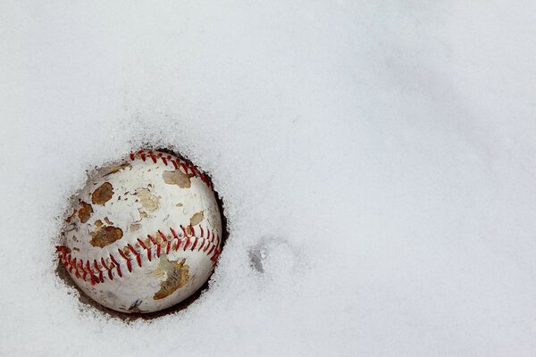 Vieille balle de baseball fissurée dans la neige