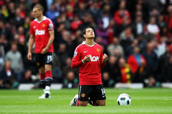 A football player on his knees with a ball on the football field