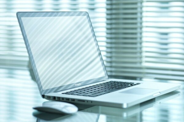 Laptop with a mouse on a glass table