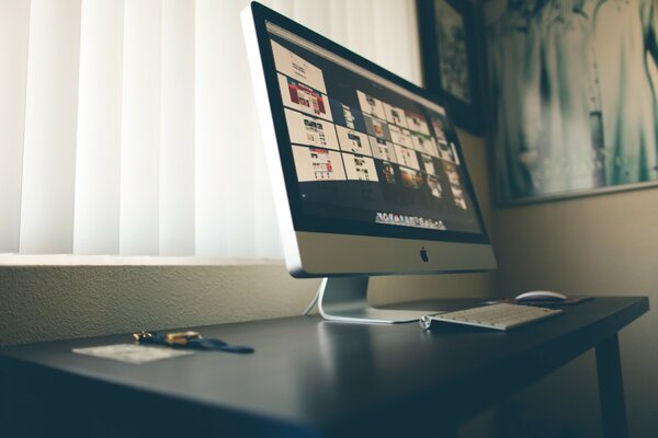 Una mesa con un iMac de pie sobre ella